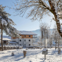 Sneeuwbedekte vakantiepark met glamping accommodaties, bomen en bergen op de achtergrond tijdens een winterdag.