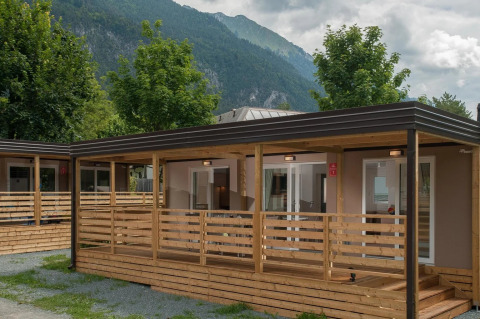 Photo de cabanes glamping dans un parc de vacances, entouré de montagnes et d’arbres, idéal pour se détendre.
