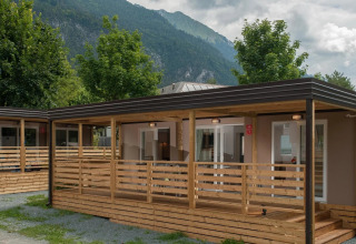 Photo de cabanes glamping dans un parc de vacances, entouré de montagnes et d’arbres, idéal pour se détendre.