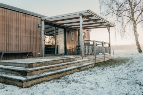 Cabaña familiar de madera con terraza cubierta y nieve, Family Lodge, Holiday park De Boshoek, Países Bajos.