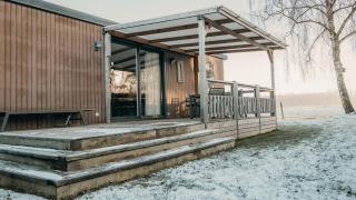 Houten lodge met overdekte veranda en sneeuw, Family Lodge bij Holiday park De Boshoek, Nederland.