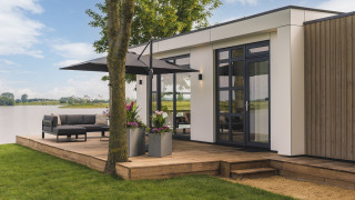 Moderno alojamiento con terraza de madera, muebles exteriores y vista al lago en MarinaPark Bad Nederrijn, Países Bajos.