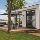 Moderne lodge med træterrasse, havemøbler og udsigt over vandet ved MarinaPark Bad Nederrijn i Holland.