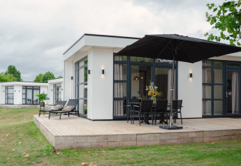 Lodge moderno Villa Maritiem con terraza de madera y muebles de exterior en MarinaPark Bad Nederrijn, Países Bajos.
