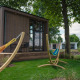Et lille træhus ved floden med hængekøjer og terrasse, omgivet af grønne træer i MarinaPark Bad Nederrijn.