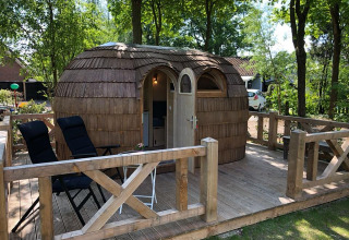 Unique wooden cabin on a deck at Camping Emmen, a holiday park in Drenthe, Netherlands, among trees.