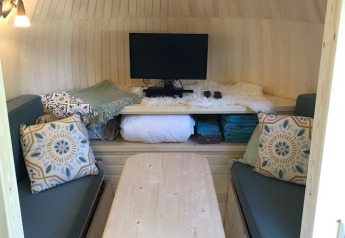 Interior of IGLO Log Cabin at Camping Emmen, Netherlands, showing sofas, wooden table, TV, and decor.