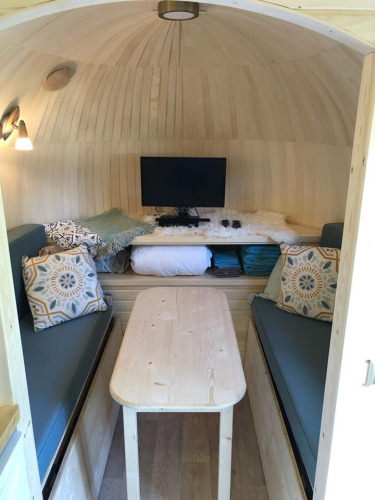 Innenraum der IGLO Log Cabin bei Camping Emmen in den Niederlanden mit Sofas, Tisch und Fernseher.