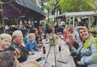 Groep mensen geniet samen van een maaltijd bij Camping Emmen, een vakantiepark in Drenthe, Nederland.