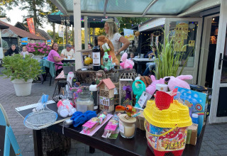 Scène extérieure à Camping Emmen, Drenthe, Pays-Bas, avec des invités et une table remplie de lots de tombola.