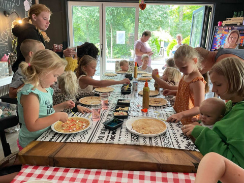 Kinderen versieren pannenkoeken samen aan tafel tijdens een activiteit op Camping Emmen in Drenthe, Nederland.