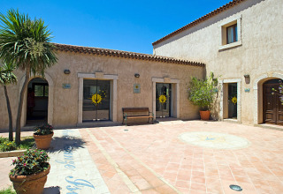Binnenplein aan Centro Vacanze Isuledda, vakantiepark in Sardinië, Italië, met terracotta & planten.