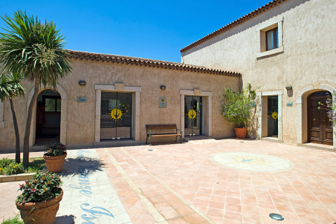 Gårdhave på Centro Vacanze Isuledda i Sardinien, Italien, med terrakottagulv og middelhavsplanter.