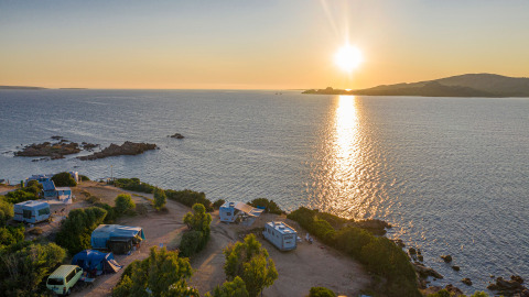 Atardecer sobre el mar en Centro Vacanze Isuledda, con caravanas y tiendas cerca de la costa en Cerdeña.