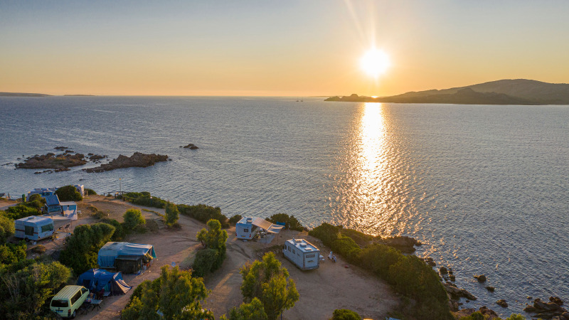 Zonsondergang boven zee bij Centro Vacanze Isuledda, campers en tenten vlak aan het water op Sardinië.