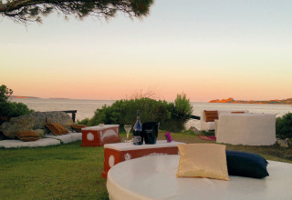 Buitenlounge bij Centro Vacanze Isuledda op Sardinië, met zicht op zee bij zonsondergang.