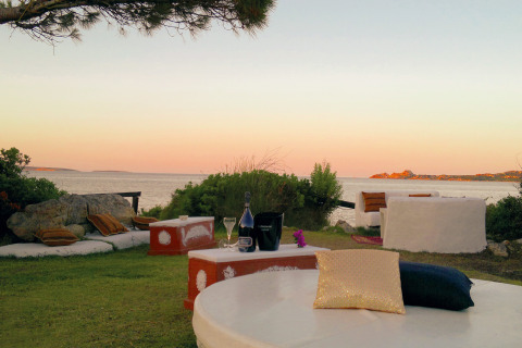 Espace lounge extérieur du Centro Vacanze Isuledda en Sardaigne, Italie, avec vue mer au coucher du soleil.