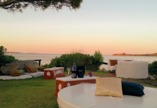 Udendørs loungeområde ved Centro Vacanze Isuledda i Sardinien, med havudsigt ved solnedgang.