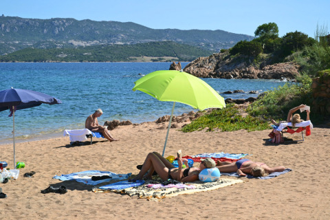Vakantiegangers ontspannen op het zandstrand met parasols bij Centro Vacanze Isuledda op Sardinië.