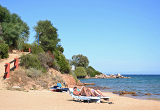 Solbadende gæster på en rolig sandstrand ved Centro Vacanze Isuledda, Sardinien, Italien, tæt ved havet.