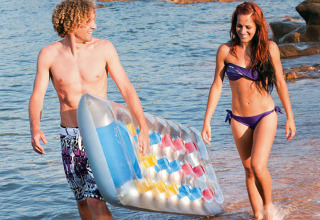 Un jeune couple marche avec un matelas gonflable à la plage du Centro Vacanze Isuledda, Sardaigne, Italie.