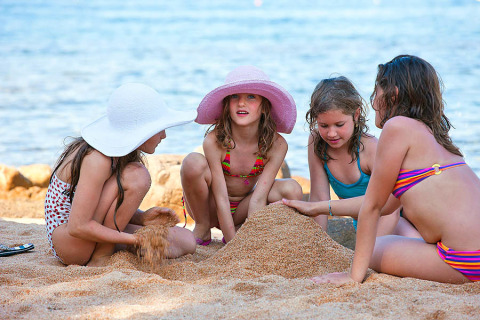 Vier kinderen bouwen een zandkasteel op het strand aan het Centro Vacanze Isuledda vakantiepark in Sardinië.