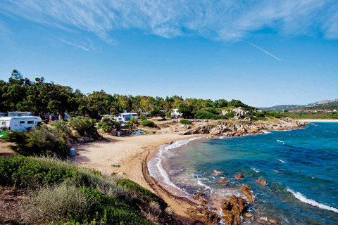 Strand bij Centro Vacanze Isuledda vakantiepark op Sardinië, Italië, met campers en groene natuur aan de kust.