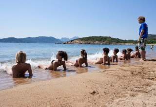 Børn slapper af på stranden i vandkanten ved Centro Vacanze Isuledda feriepark, Sardinien, Italien.