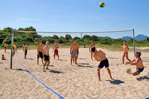 Jongeren spelen beachvolleybal in het zand aan het Centro Vacanze Isuledda vakantiedomein op Sardinië, Italië.