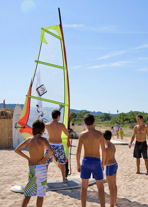 Bambini imparano il windsurf sulla spiaggia al Centro Vacanze Isuledda, villaggio turistico in Sardegna, Italia.