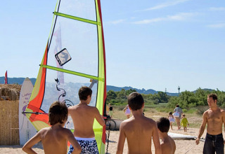 Børn lærer windsurfing på stranden i Centro Vacanze Isuledda feriepark, Sardinien, Italien.