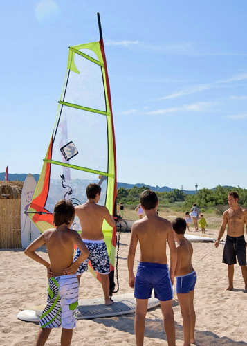 Children learning windsurfing on the beach at Centro Vacanze Isuledda holiday park, Sardinia, Italy.