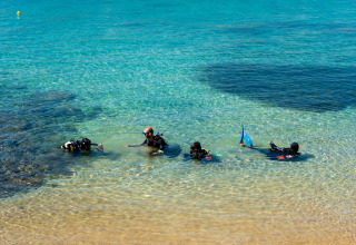 Duikers oefenen in het glasheldere water bij Cannigione di Arzachena, Sardinië, Italië, dicht bij de kust.