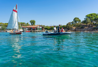 Folk nyder sejlsport og både på det klare blå vand ved Centro Vacanze Isuledda, Sardinien, Italien.
