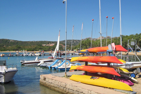 Kajaks, boten en zeilboten in een drukke haven bij vakantiepark Centro Vacanze Isuledda op Sardinië, Italië.