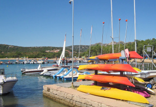 Kayaks, barcos y veleros en un puerto concurrido del parque vacacional Centro Vacanze Isuledda en Cerdeña, Italia.