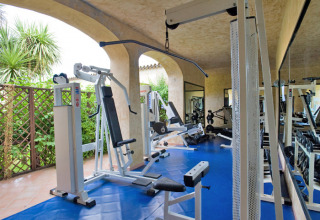 Fitnessrum med moderne udstyr og spejle på Centro Vacanze Isuledda feriepark i Sardinien, Italien.