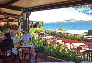 Buitenrestaurant bij Centro Vacanze Isuledda (Suncamp) op Sardinië met uitzicht op zee en etende gasten.