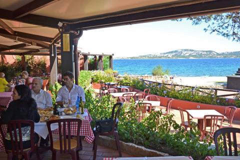 Udendørs restaurant på Centro Vacanze Isuledda (Suncamp) i Sardinien med udsigt over havet og bjerge.