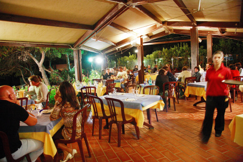 Buiten tafelen bij Centro Vacanze Isuledda, een vakantiepark op Sardinië, Italië, met gasten 's avonds.