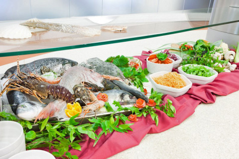 Selección de pescado y marisco fresco con verduras y hierbas en un bufé en Cerdeña, Italia.
