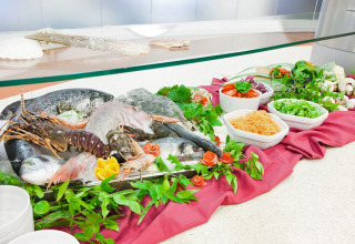 Selection of fresh fish and seafood with vegetables and herbs on display at a buffet in Sardinia, Italy.