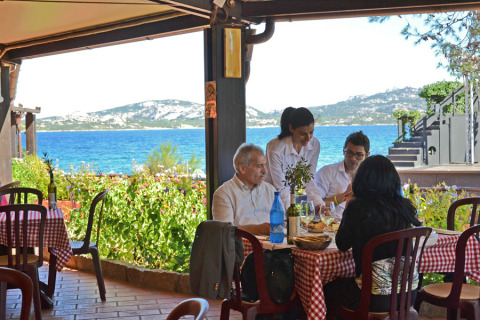 Quatre personnes dînent dans un restaurant face à la mer au Centro Vacanze Isuledda, Sardaigne, Italie.