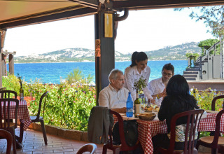 Quattro persone cenano in un ristorante vista mare al Centro Vacanze Isuledda, Sardegna, Italia.