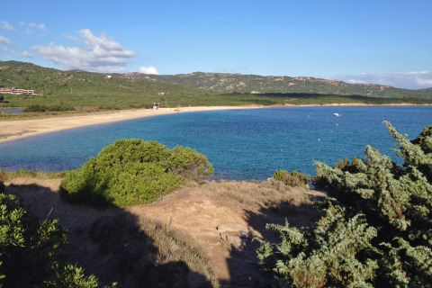 Uitzicht op het strand en blauwe zee aan Centro Vacanze Isuledda vakantiepark in Sardinië, Italië.