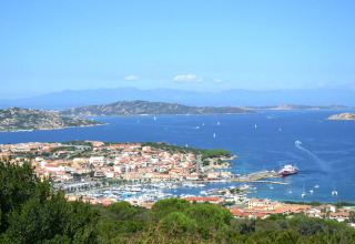 Udsigt over Centro Vacanze Isuledda med ferieboliger, marina og blåt hav på Sardinien, Italien.