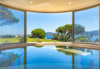 Binnenzwembad met panoramisch zicht op tuin, zee en heuvels bij Centro Vacanze Isuledda, Sardinië.