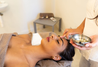 Vrouw krijgt een ontspannende gelaatsbehandeling met olie in het wellnesscenter van Isuledda, Sardinië.