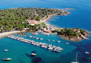 Aerial view of Centro Vacanze Isuledda holiday park in Sardinia with marina, beach, and lush greenery.