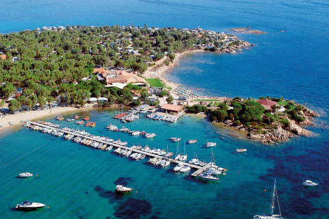 Aerial view of Centro Vacanze Isuledda holiday park in Sardinia with marina, beach, and lush greenery.